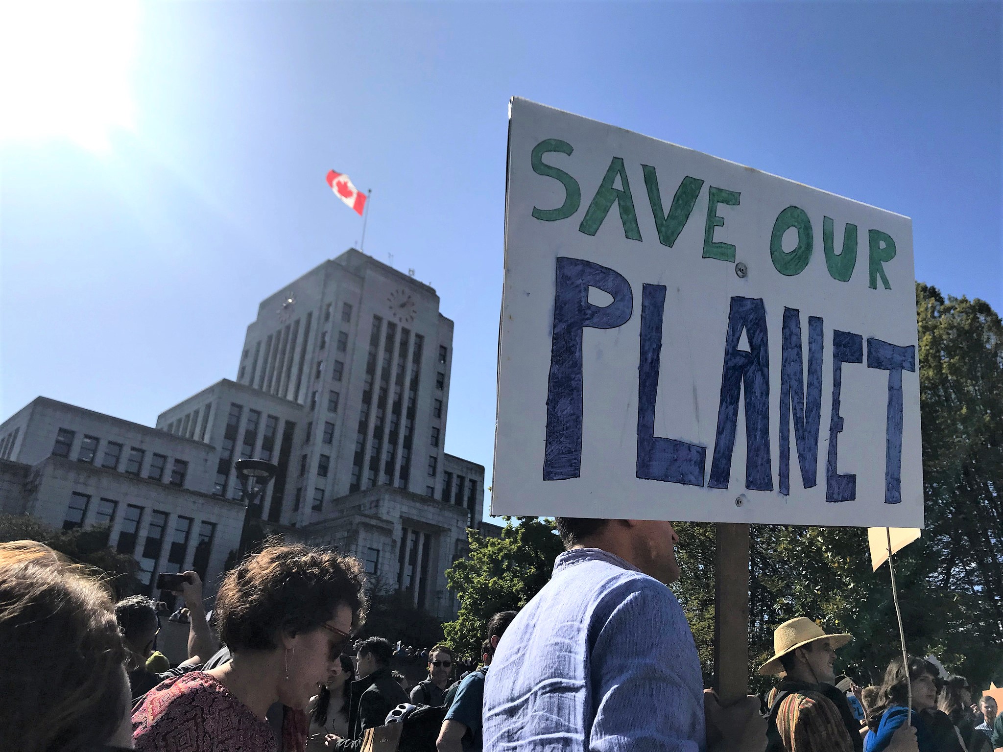 Person carrying "Save our Planet" sign in front of Vancouver City Hall
